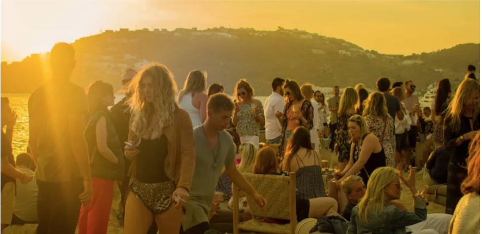 Lots of different people stood on the beach, celebrating at a festival.