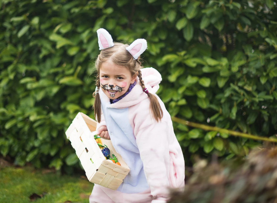 girl wearing rabbit ears carrying a tray of easter eggs