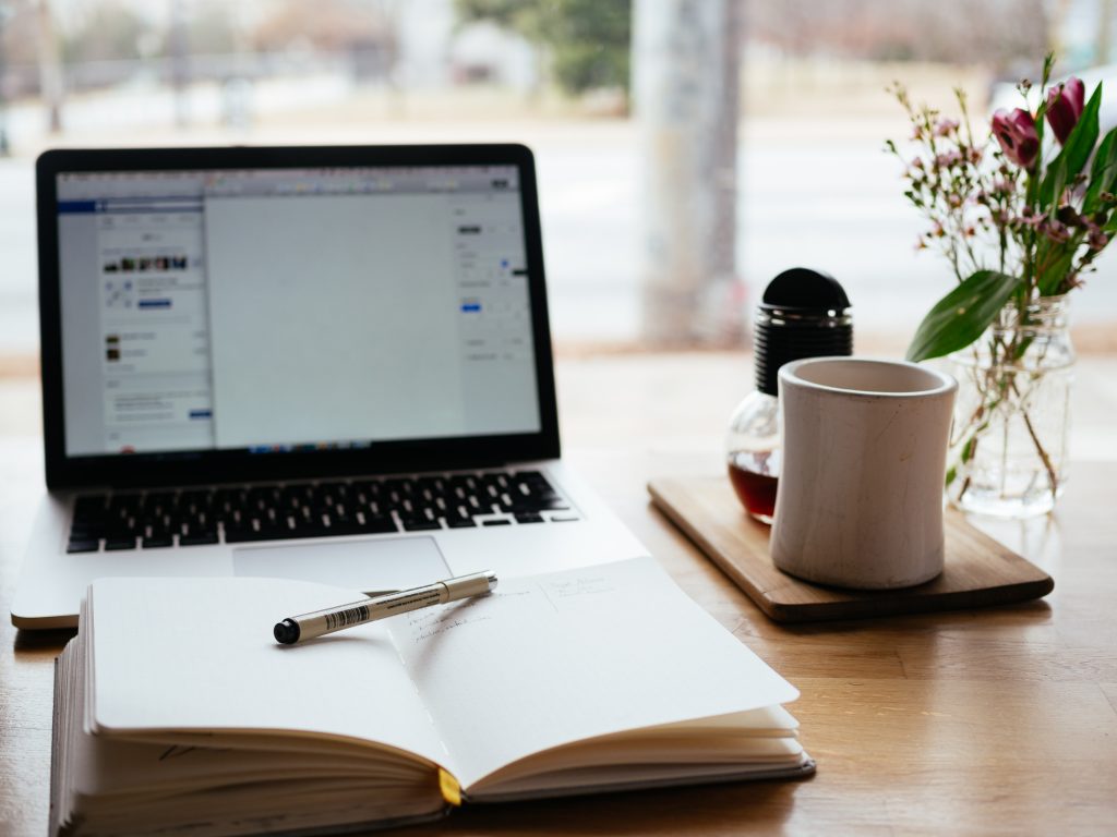 A computer and open journal on a table 