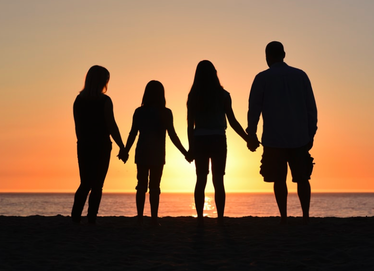 Four people stood in a sunset holding hands