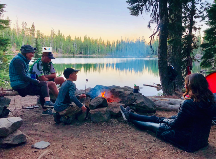 A family group sat around a campfire holding marshmallows on sticks.