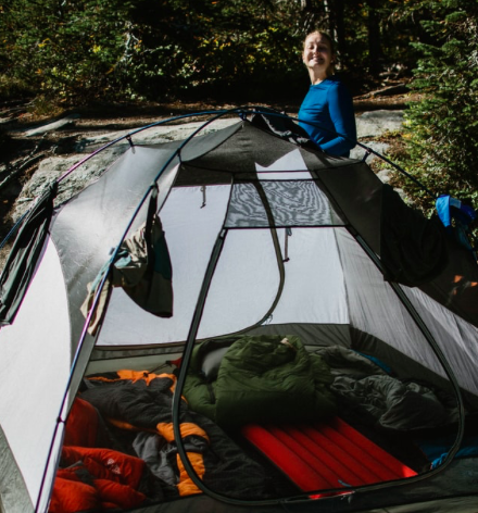 A woman smiling stood next to her tent