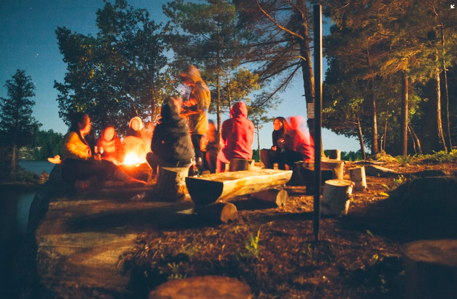 A group of people sitting around a campfire together