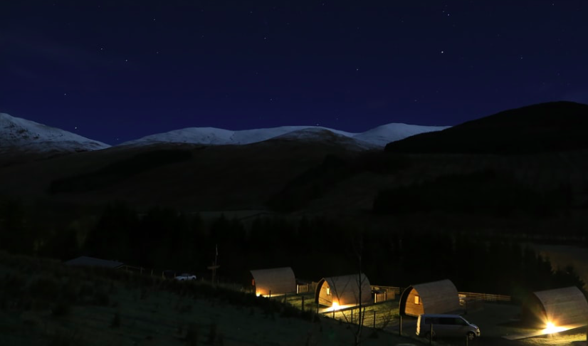 Five glamping pods with lights at night time