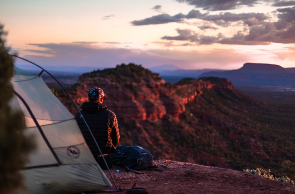 A man sat with his back to us, looking over the mountain top 