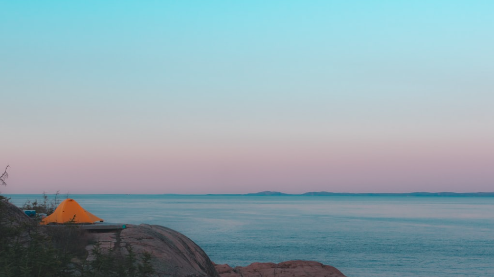 A yellow tent on a cliff overlooking the sea